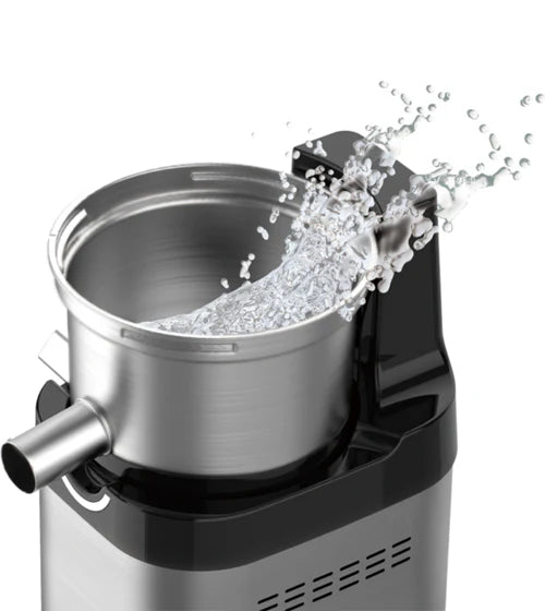 Nahaufnahme aus der Vogelperspektive im Studio der gebürsteten Edelstahl-Entsafterschüssel-Komponente, montiert auf der Basis eines Kuvings Chef CS700 Gewerbe-Slow-Juicers, die dynamisch eine saubere Wasserfontäne zeigt, die aus der offenen Oberseite spritzt, um die einfache Reinigung zu veranschaulichen, auf solidem weißem Hintergrund.
