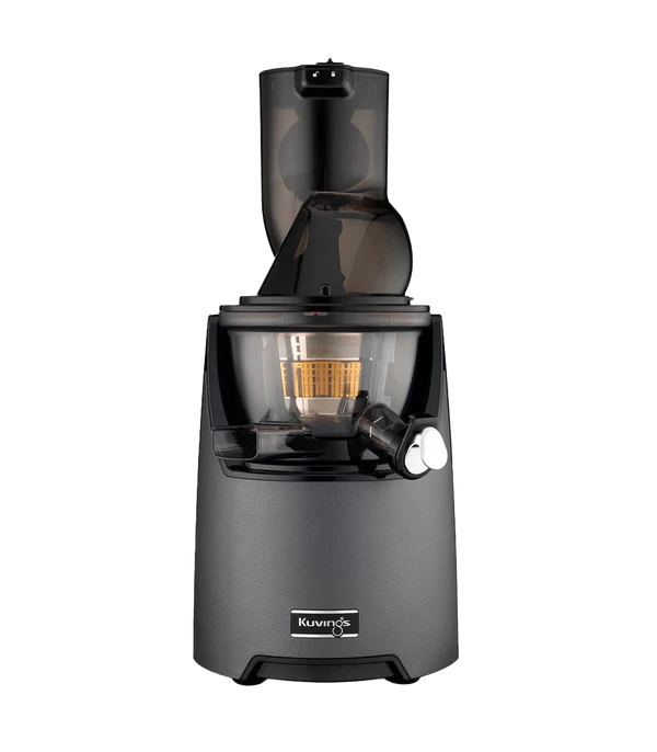 Three-quarter studio product shot of a Kuvings EVO820 whole slow juicer featuring a textured gunmetal graphite grey motor base with a black Kuvings logo badge, assembled with its dark translucent juicing bowl and wide-mouth O-shape feeding chute against a transparent checkered background.