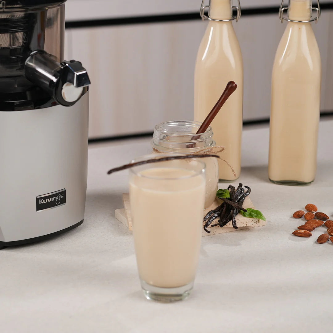 Homemade almond milk with vanilla, almonds and Kuvings slow juicer in a modern kitchen setting.